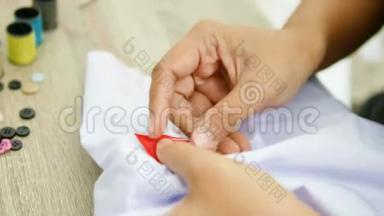一个女人在白色衬衫上缝一个红色标志时，要紧紧抓住她的手